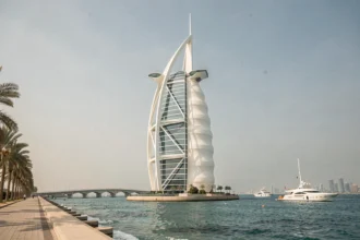Vue extérieure grand angle du Burdž Al Arab à Dubaï, hôtel emblématique en forme de voile se reflétant sur le golfe Arabique en 2026