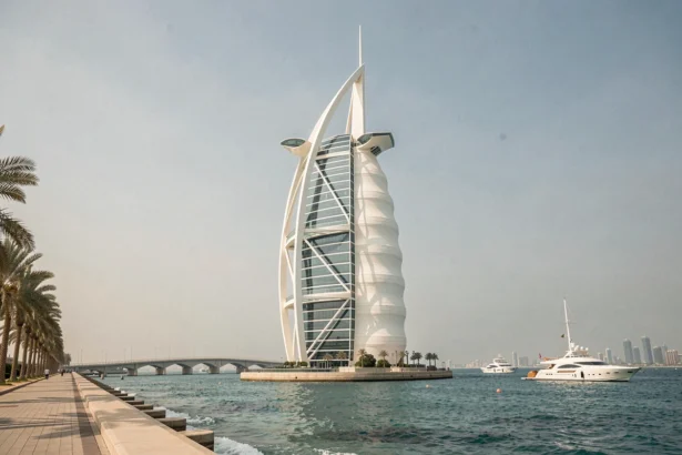 Vue extérieure grand angle du Burdž Al Arab à Dubaï, hôtel emblématique en forme de voile se reflétant sur le golfe Arabique en 2026