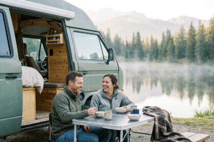 Couple souriant prenant le petit déjeuner près du lac