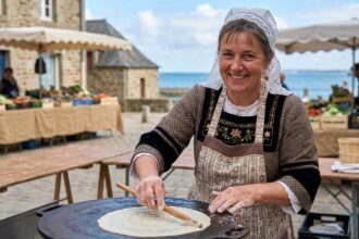 Femme bretonne souriante préparant des crepes traditionnelles