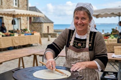 Femme bretonne souriante préparant des crepes traditionnelles