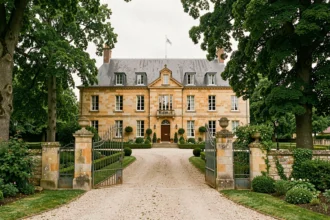 Vue d'ensemble d'un manoir normand en pierre avec jardin verdoyant dans l'Eure, représentant les meilleurs hôtels de la région
