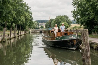 Couple sur une péniche naviguant sur le canal de Bourgogne entouré de verdure
