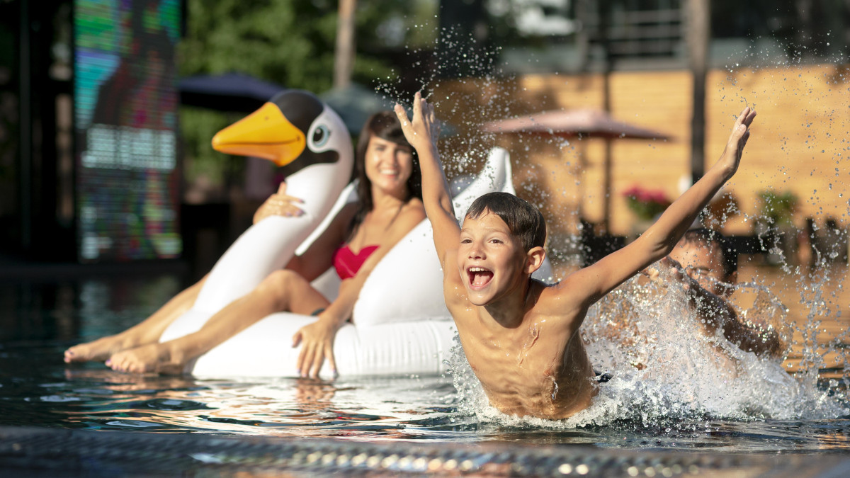 Un jeune garçon s'amuse dans la piscine d'un camping en compagnie de sa mère.